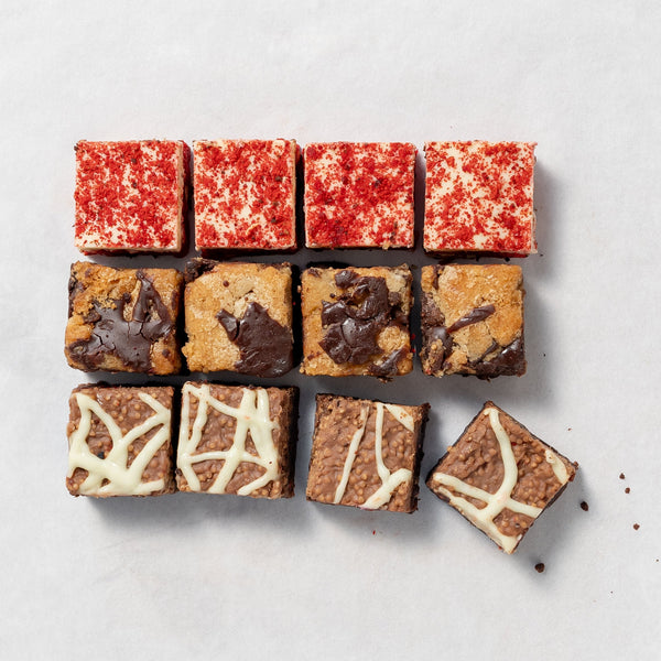 A box of assorted brownies with different toppings and fillings, presented in a visually appealing arrangement.