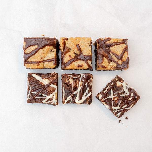 A selection of chocolate brownies arranged on a neutral surface, showcasing different textures and toppings.