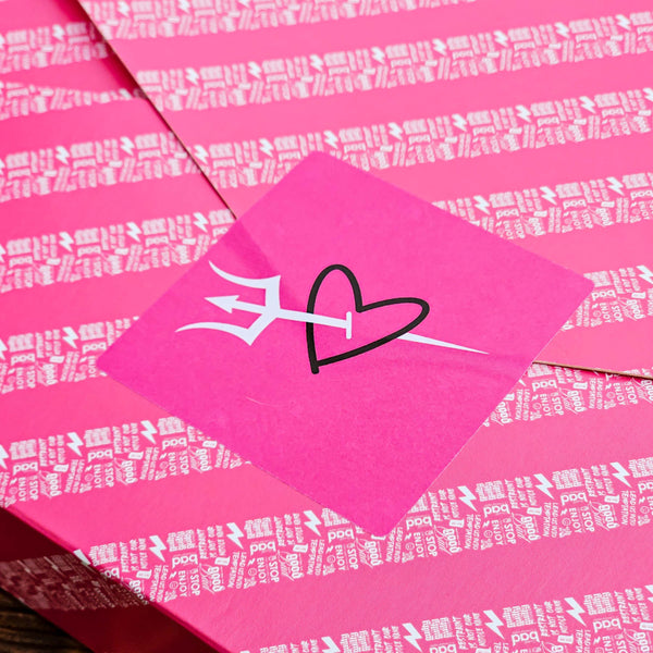 A close-up of pink gift wrap with a heart and arrow graphic design on it.