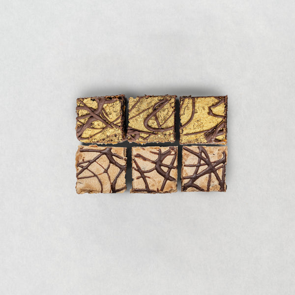 Six vegan and gluten free square brownies with different chocolate drizzle patterns on a light gray background