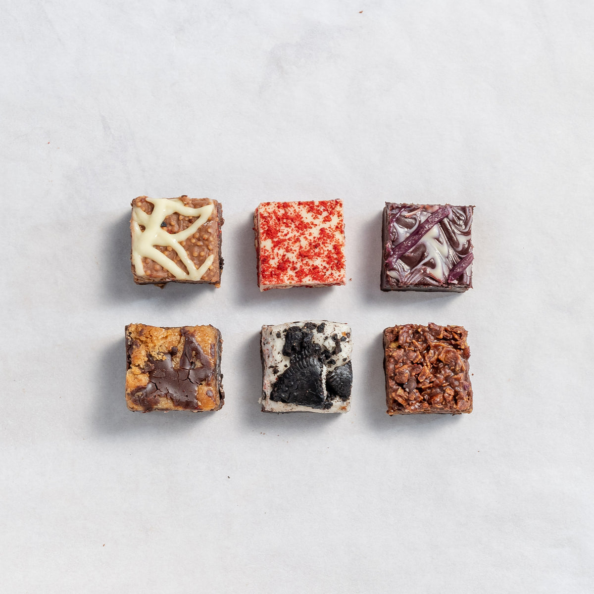 Assorted flavoured chocolate brownies on a neutral background