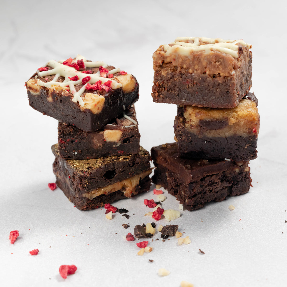 6 squares of flavoured chocolate brownies in 2 stacks of 3 on white background