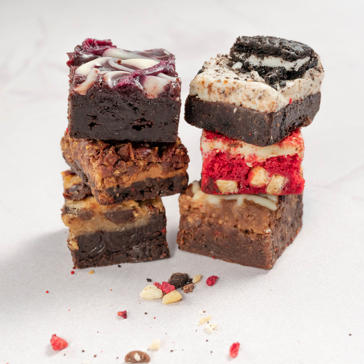 6 delicious flavoured chocolate brownies with different fillings and toppings stacked into two columns on a neutral background