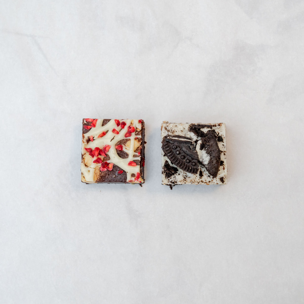 raspberry white chocolate brownie and Oreo cookies and cream brownie on a neutral background