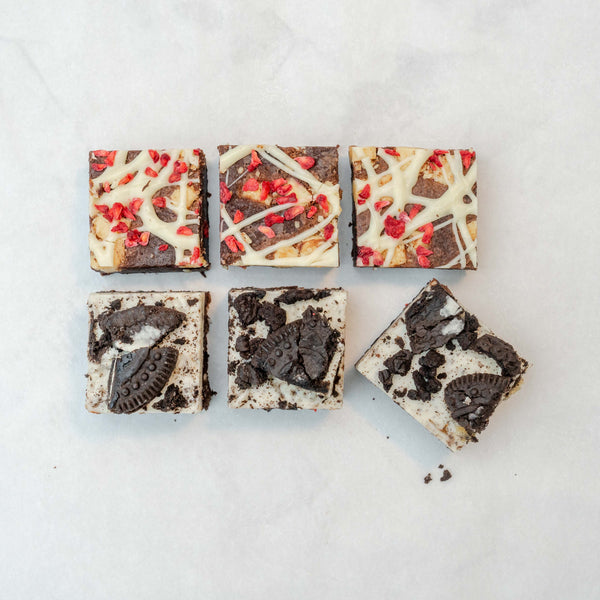 An array of six brownie bites from the Discovery 6 Bite Brownie Box, showcasing different flavors with visible chunks of raspberry and cookies.
