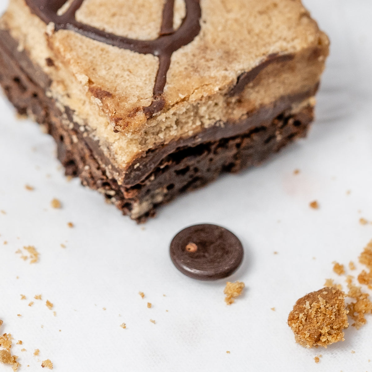 Close-up of a layered vegan gluten free chocolate brownie with chocolate and cookie dough on a white background