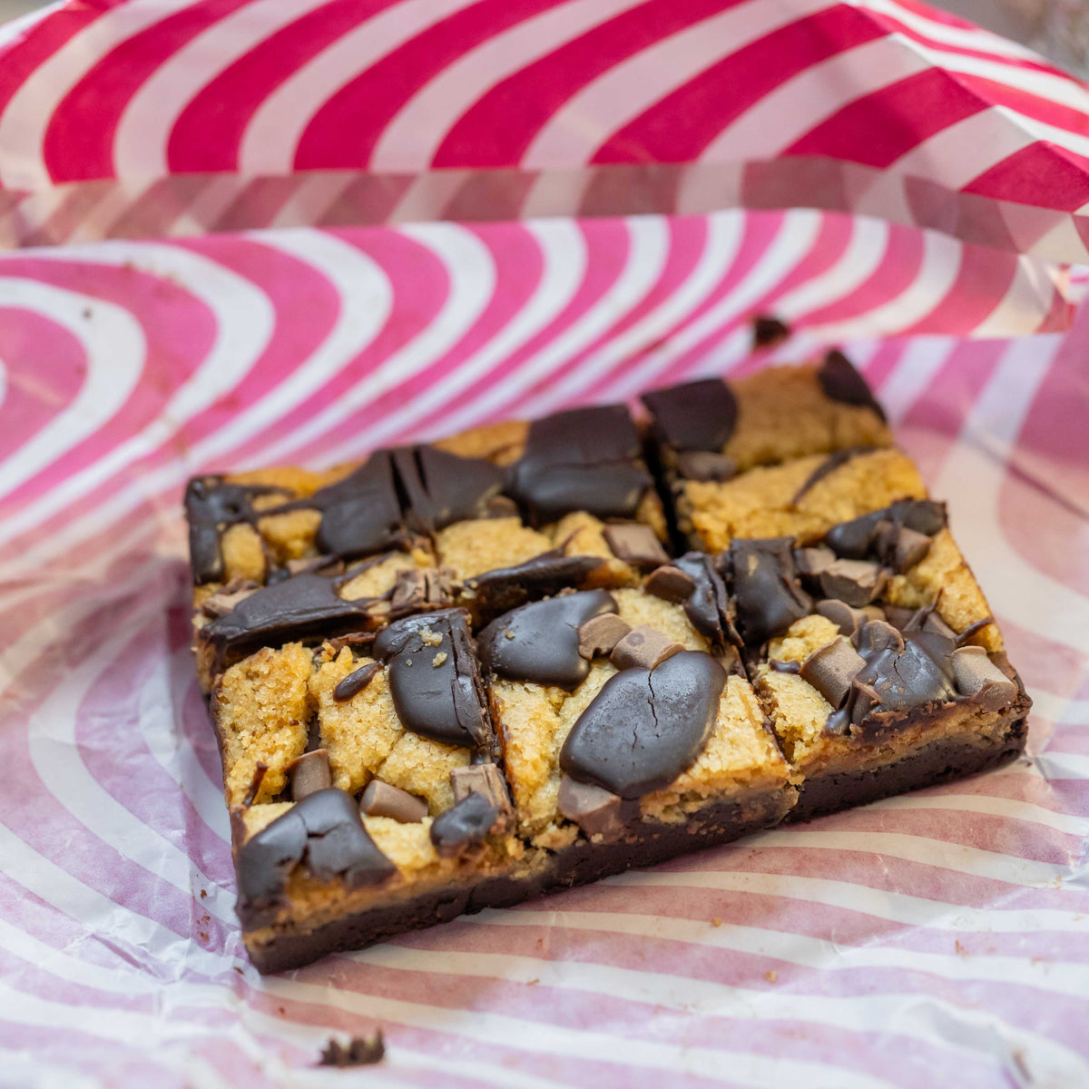Close-up of some unwrapped chocolate brownie cookie brookies with a rich, dark chocolate layer on a striped background