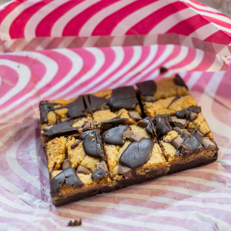 Close-up of some unwrapped chocolate brownie cookie brookies with a rich, dark chocolate layer on a striped background