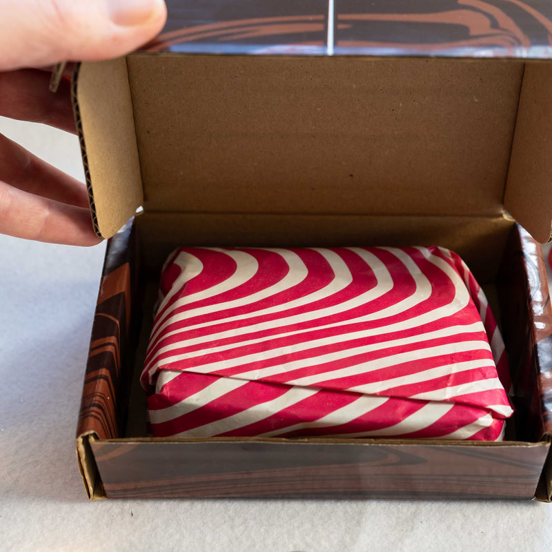 Open box with red and white striped gift inside, containing chocolate brownies
