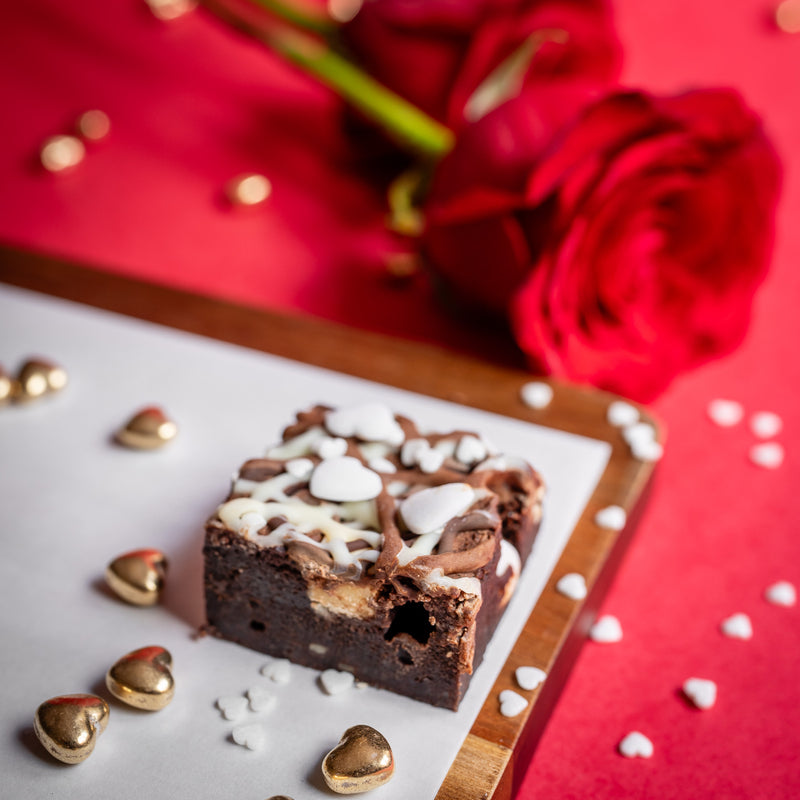 Triple Chocolate Bad Brownie with white and chocolate decorations on a red background with roses
