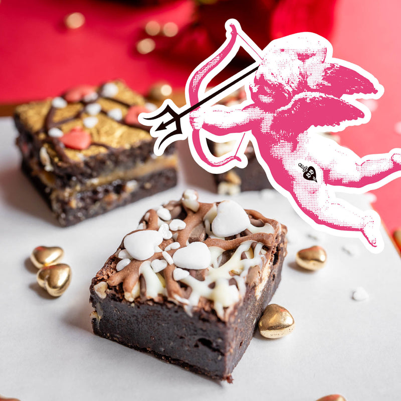 Dark Chocolate brownies with white frosting and gold leaf on a white surface with a red background.