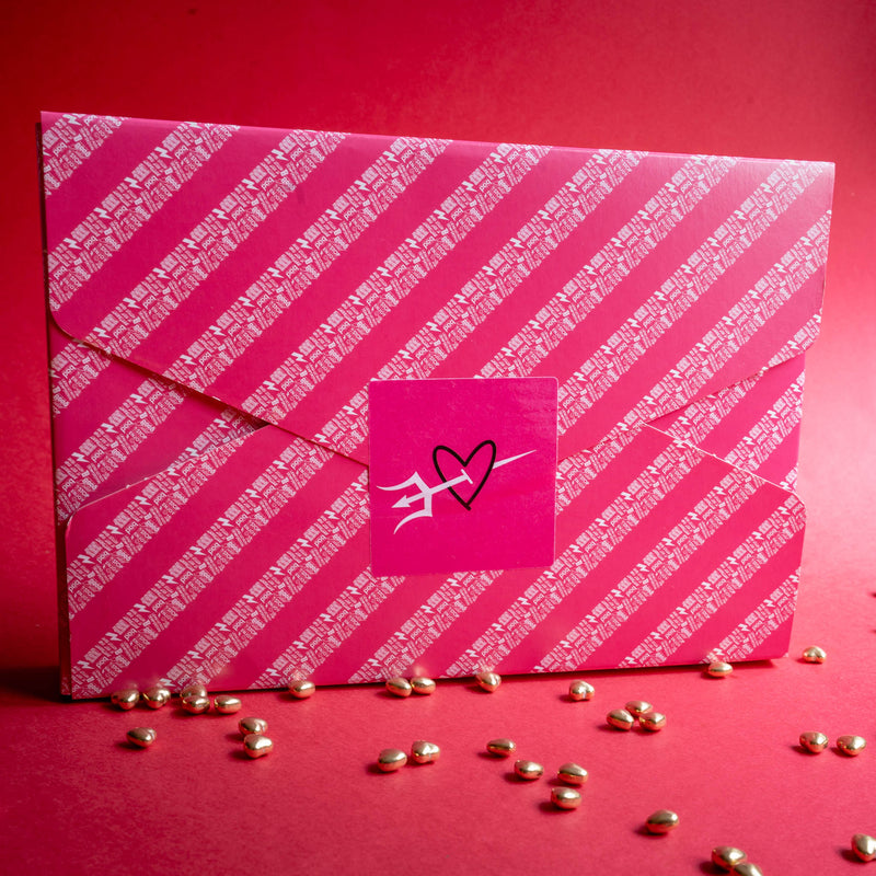 Pink gift wrapped box of Bad Brownie  postal chocolate brownies with white diagonal stripes and a heart logo on a red background