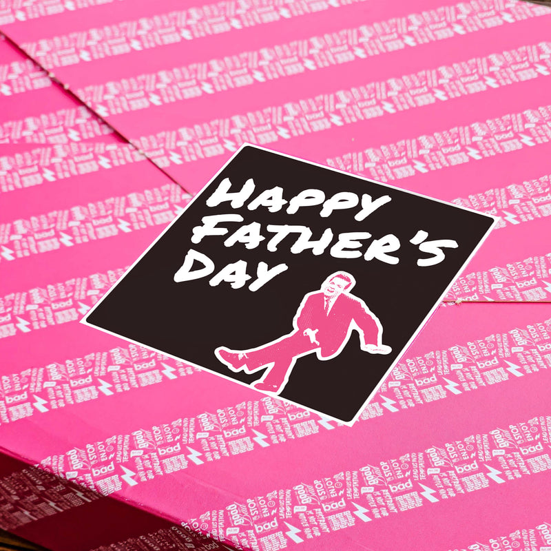 Pink gift wrapped box of brownies with a black Happy Father's Day Sticker, on a wooden tabletop