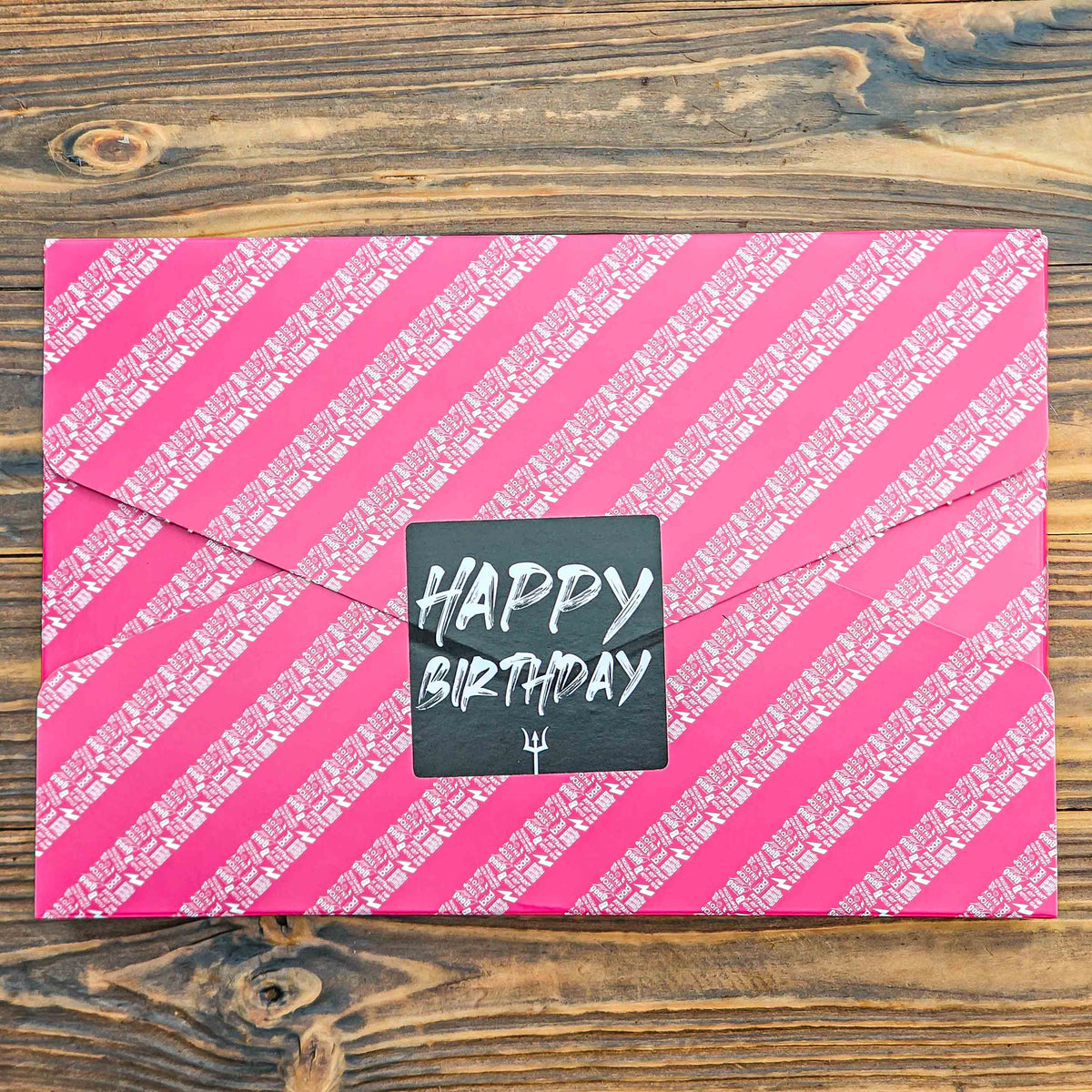 Pink striped birthday card with 'Happy Birthday' text on a wooden surface