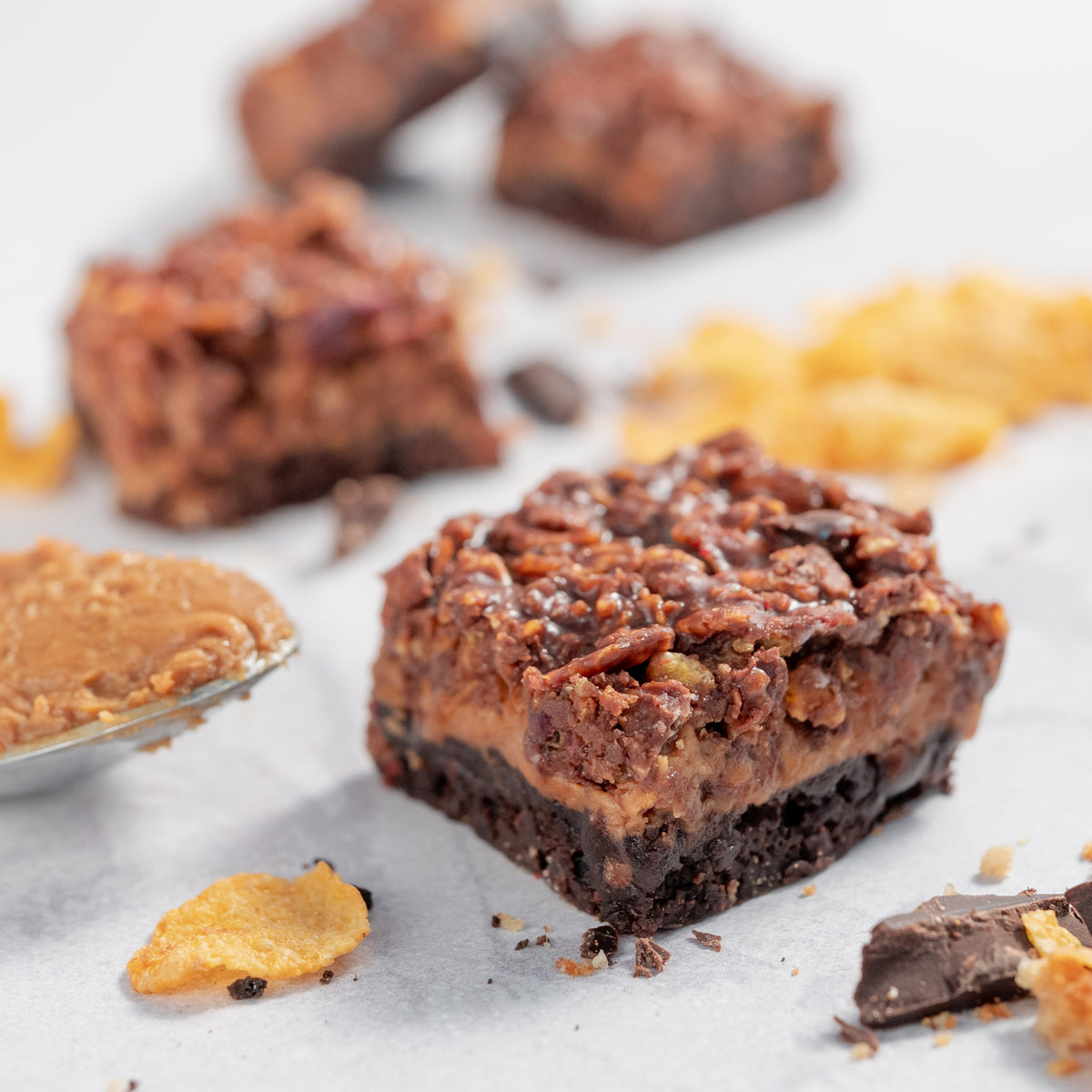 Close up photo of biscoff and cornflake dark chocolate brownies with cornflakes and chocolates scattered around