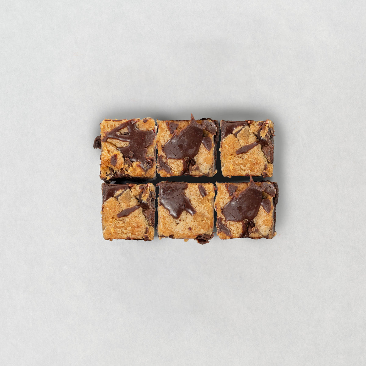 Chocolate brownie and cookie brookie cut into squares on a light gray background