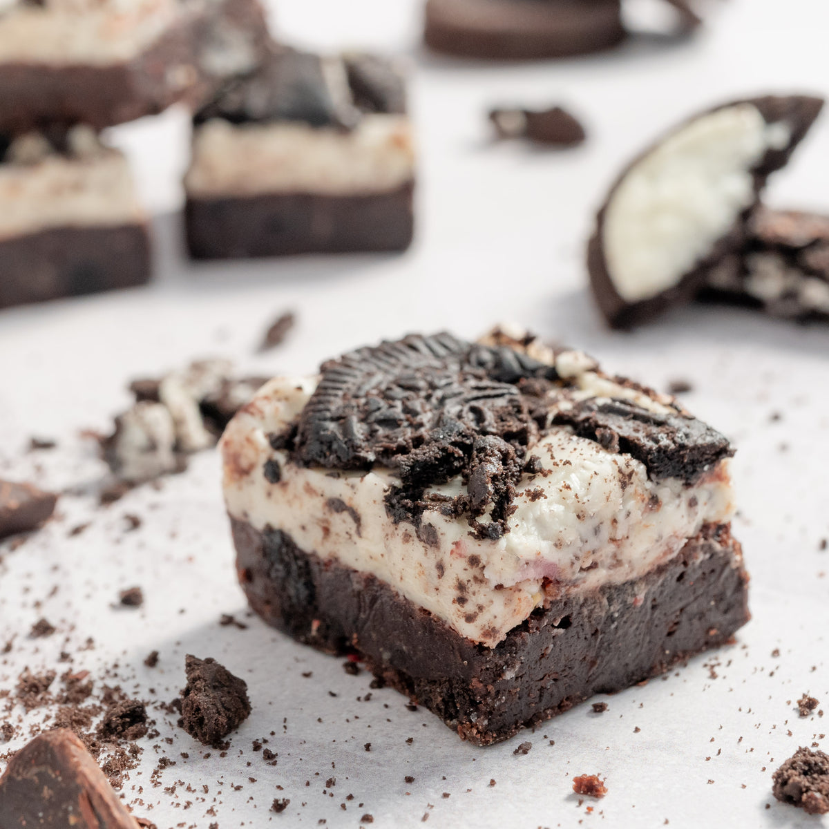 Close up photo of Oreao cookies and cream dark chocolate brownies with cookies and chocolates scattered around