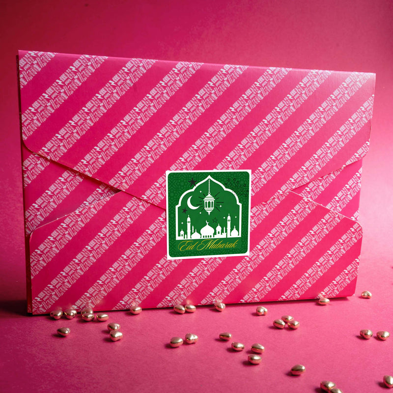 Pink gift box with white text and a green 'Eid Mubarak' sticker on a pink background
