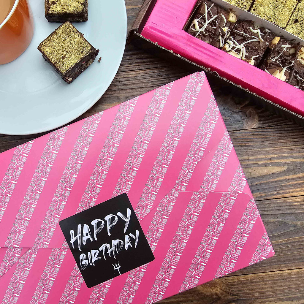 overhead shot of table with box of brownies in the corner and a cup of tea with a pink gift wrapped happy birthday brownie box in the centre