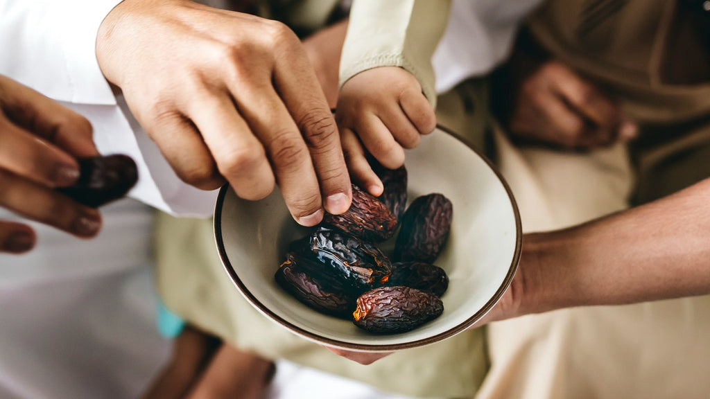 People reaching for dates in a bowl for Iftar and Ramadan with a blurred background
