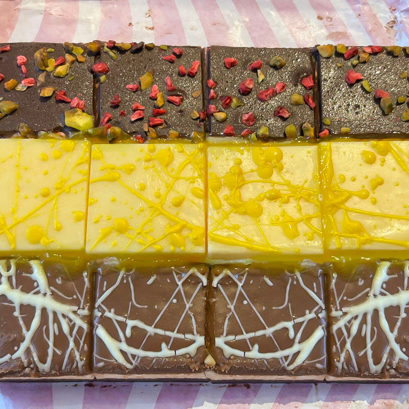 Assorted chocolate brownies with different toppings on a pink and white striped background