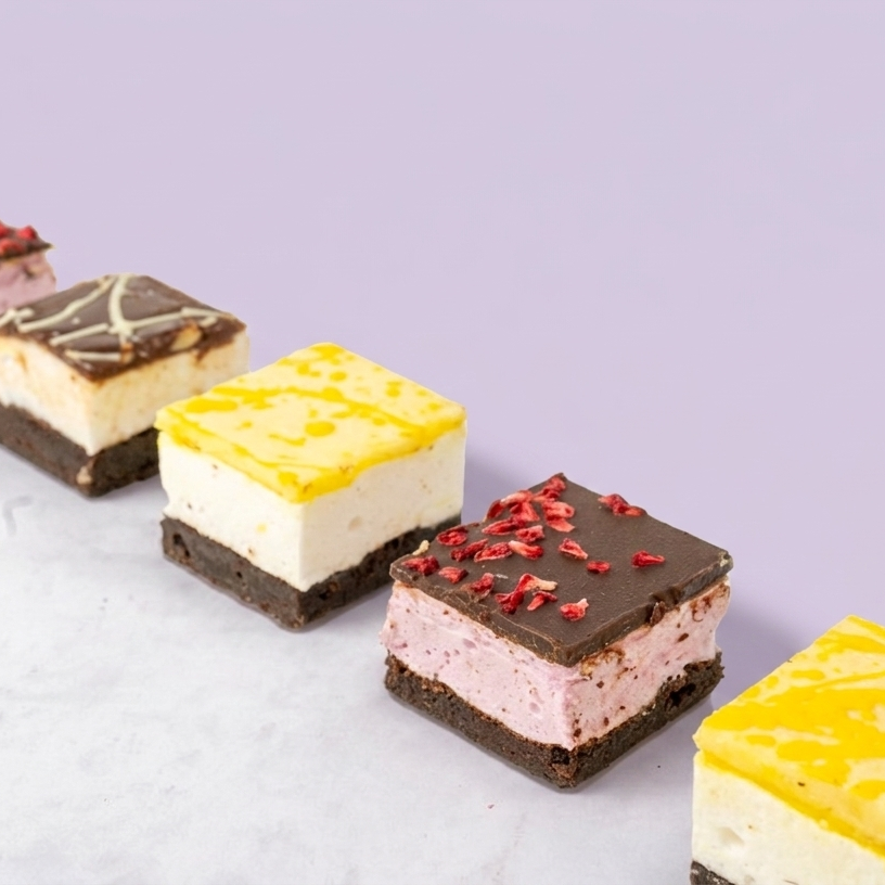 Row of small marshmallow brownies with different flavours on a light purple background