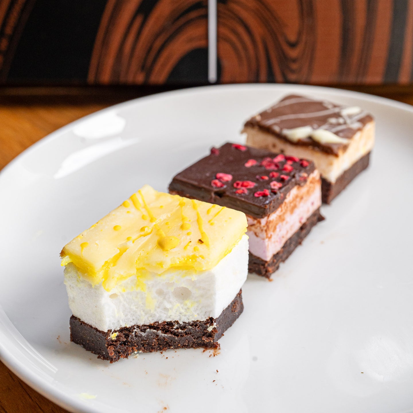 3 marshmallow and brownie bites, in different flavours on a plate in front of a bad brownie box