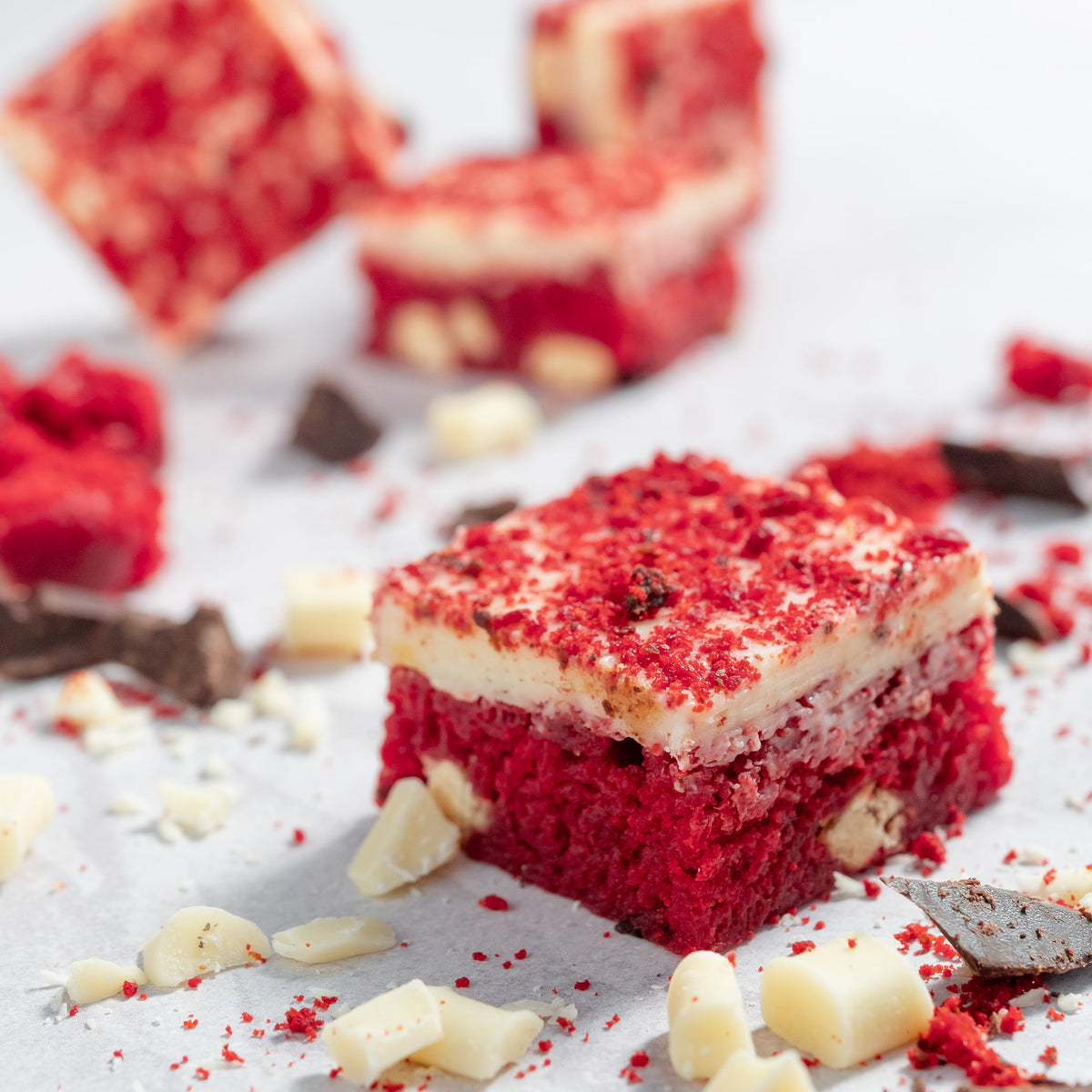 Close up photo of red velvet chocolate blondies with white and milk chocolate pieces scattered around