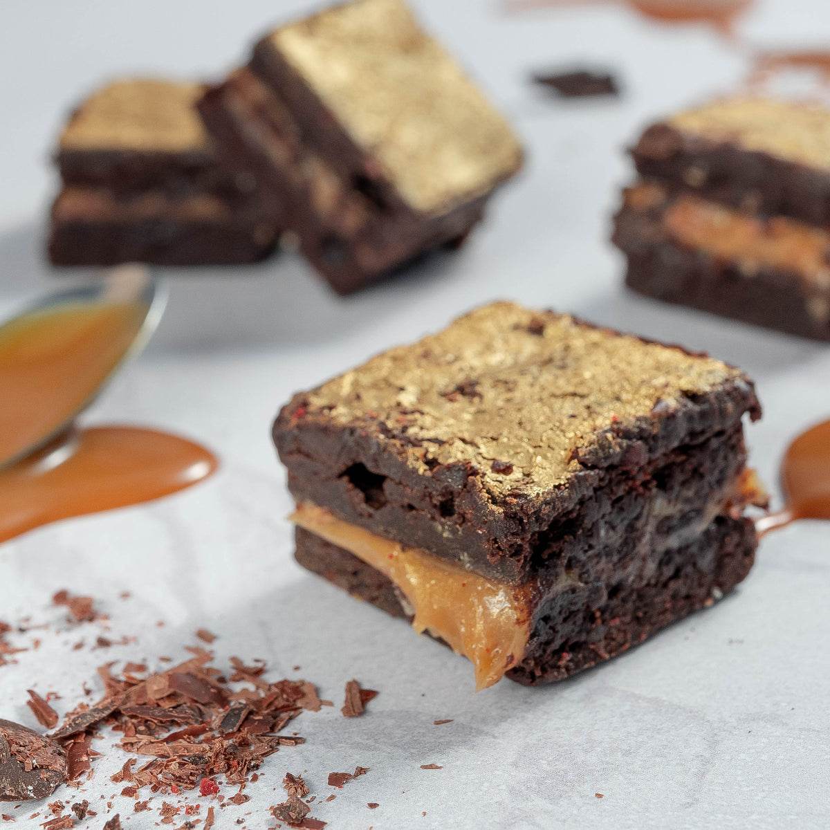close up picture of a gooey salted caramel dark chocolate brownie with chocolate chips and caramel pools on a neutral background