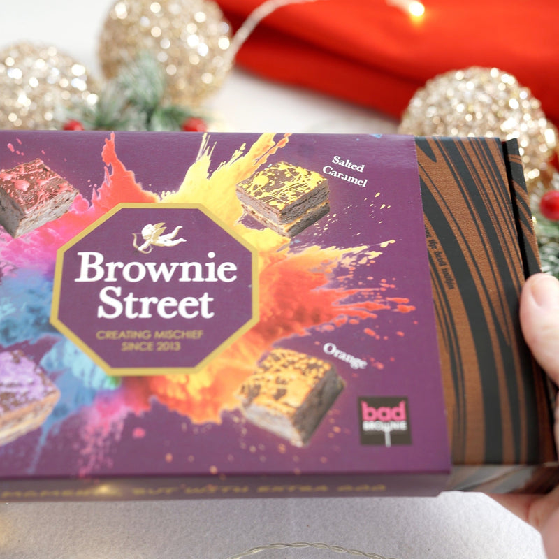 Brownie Street packaging held by a hand with festive lights and decorations in the background