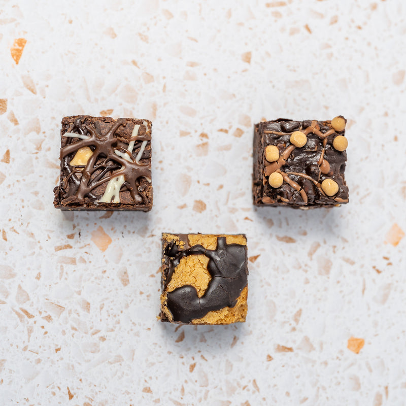 Three different chocolate brownies on a textured white surface
