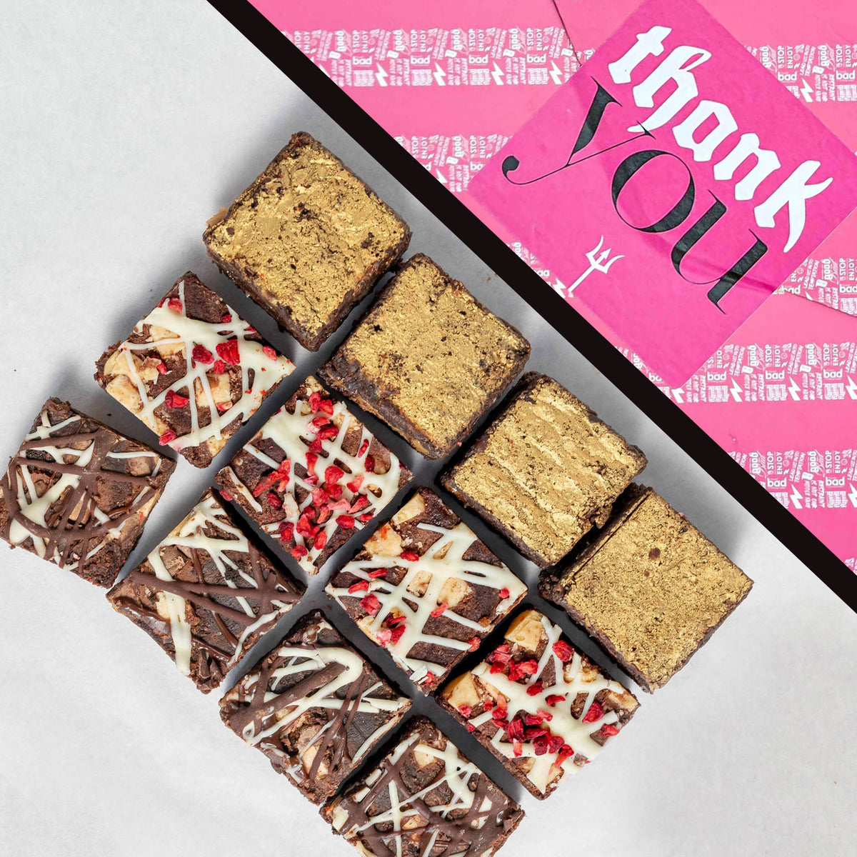 The Bestsellers 12 Bite Brownie Box in Thank You gift wrap. Assorted brownies on a white surface with a pink 'thank you' giftwrap in the background.