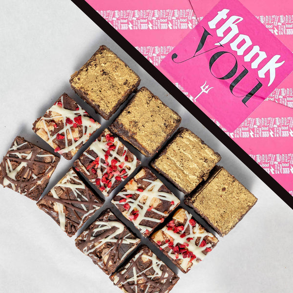 Assorted brownies on a white surface with a pink 'thank you' giftwrap in the background.