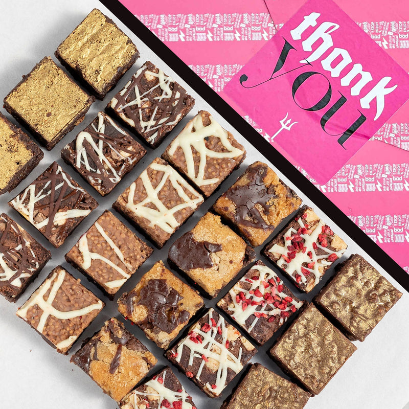 Assorted brownies on a white surface with a pink 'thank you' giftwrap in the background.