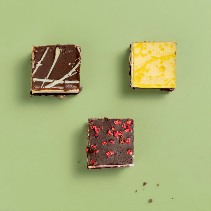 Three different chocolate brownie marshmallow flavours with various toppings on a green background